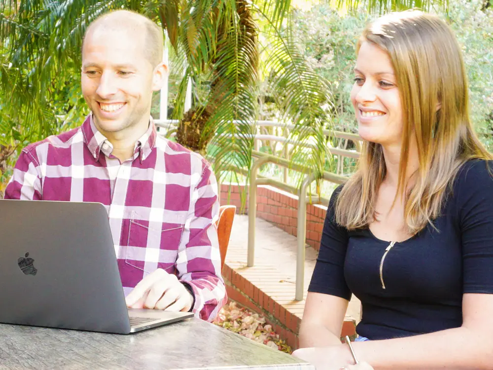 De Digital Soulmate zit achter zijn laptop en bespreekt iets met een vrouwelijke klant.